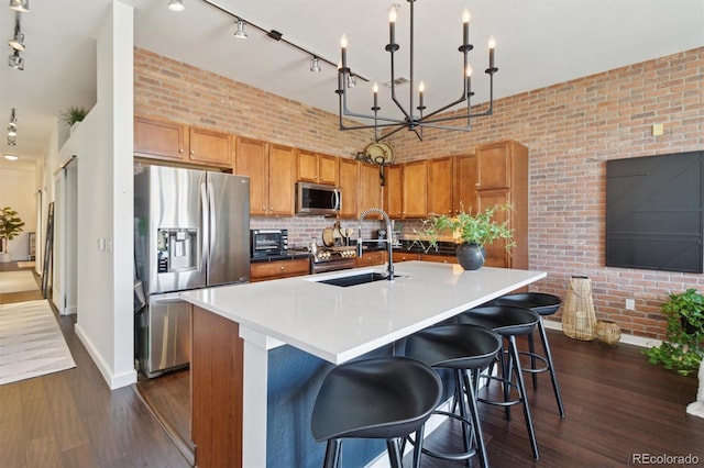 7240 W Custer Ave Unit 303, Lakewood, CO 80226 - kitchen with appliances with stainless steel finishes, a sink, dark wood finished floors, baseboards, and brick wall