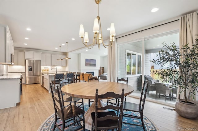 14423 Shasta Daisy Ln, Parker, CO 80134 - dining space featuring light wood-style floors, a chandelier, recessed lighting, and a fireplace