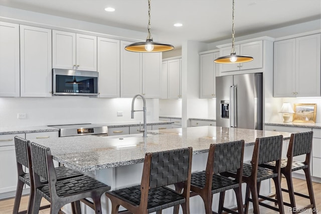 14423 Shasta Daisy Ln, Parker, CO 80134 - kitchen with appliances with stainless steel finishes, decorative light fixtures, a kitchen breakfast bar, a kitchen island with sink, and recessed lighting