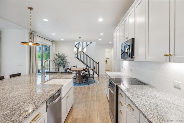 14423 Shasta Daisy Ln, Parker, CO 80134 - kitchen with appliances with stainless steel finishes, light wood-type flooring, recessed lighting, white cabinets, and hanging light fixtures