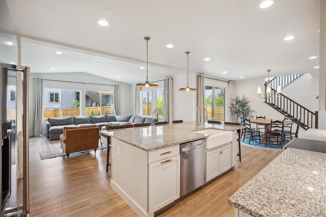 14423 Shasta Daisy Ln, Parker, CO 80134 - kitchen with stainless steel dishwasher, vaulted ceiling, white cabinets, light wood finished floors, and light stone counters
