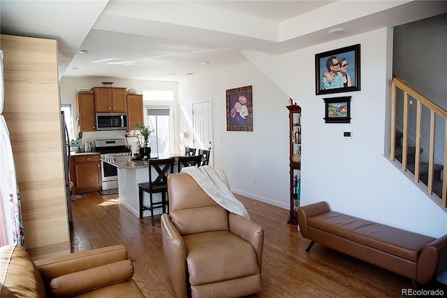 living area featuring stairway, baseboards, and dark wood finished floors