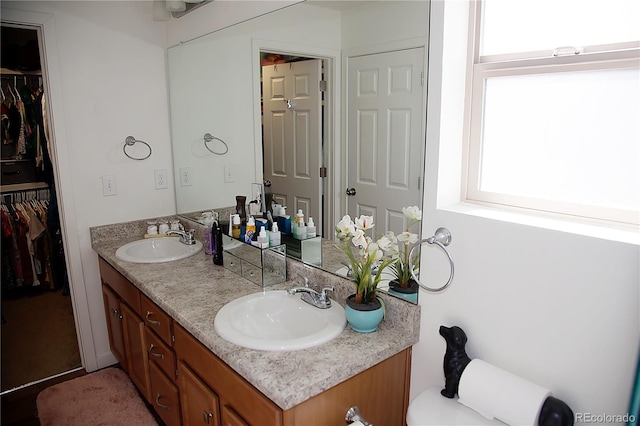 full bathroom with double vanity, a walk in closet, and a sink