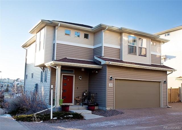 view of front of property featuring fence, driveway, and an attached garage