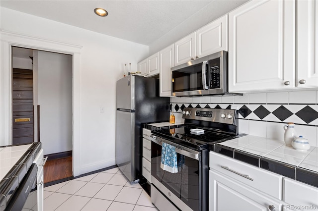 1475 N Humboldt St Unit 20, Denver, CO 80218 - kitchen with stainless steel appliances, tile counters, white cabinetry, decorative backsplash, and recessed lighting