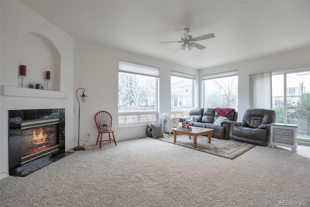carpeted living room with a fireplace with flush hearth, a ceiling fan, and a wealth of natural light