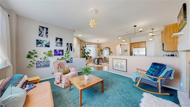 carpeted living area with arched walkways and baseboards