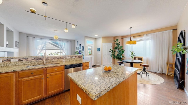 kitchen with brown cabinetry, dark wood-style flooring, dishwasher, and a sink