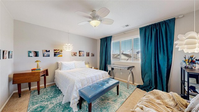 carpeted bedroom featuring visible vents, ceiling fan with notable chandelier, and baseboards