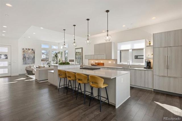 kitchen featuring a large island, sink, dark wood-type flooring, a breakfast bar area, and hanging light fixtures