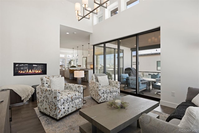 living room featuring dark hardwood / wood-style floors, an inviting chandelier, and a towering ceiling