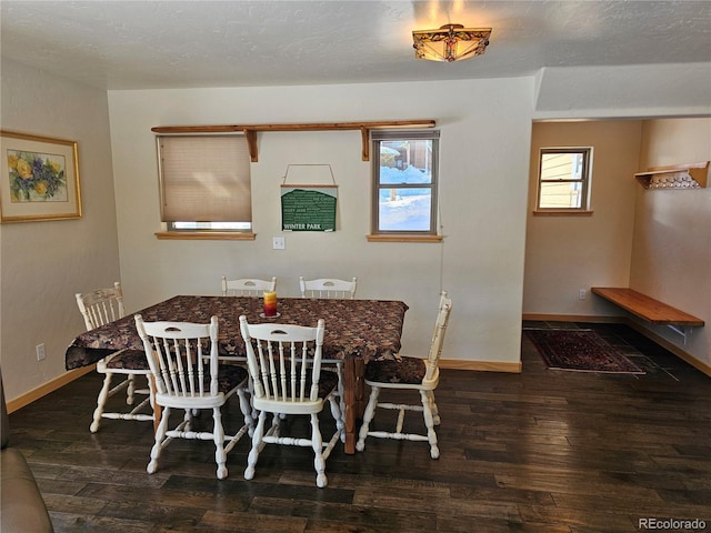 dining space with hardwood / wood-style flooring, baseboards, and a textured ceiling