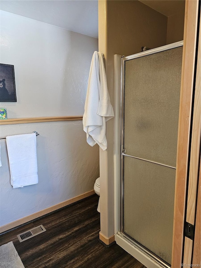 full bath with baseboards, a shower stall, visible vents, and wood finished floors