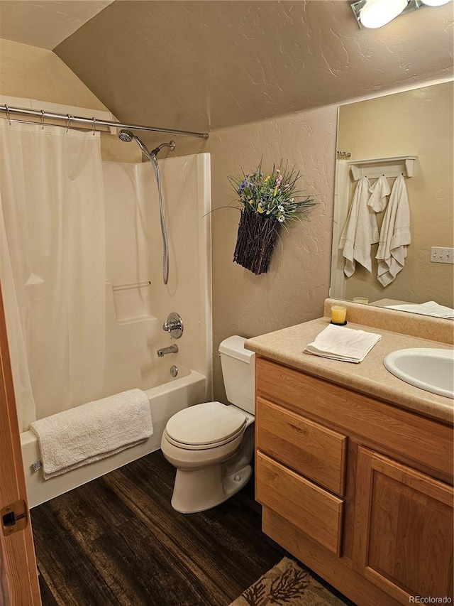 bathroom with a textured wall, toilet, wood finished floors, vanity, and shower / bath combination with curtain