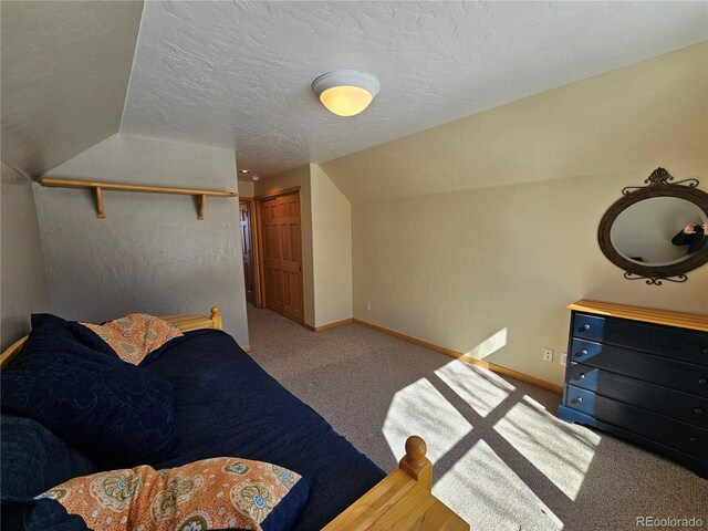 carpeted bedroom with vaulted ceiling, a textured ceiling, and baseboards