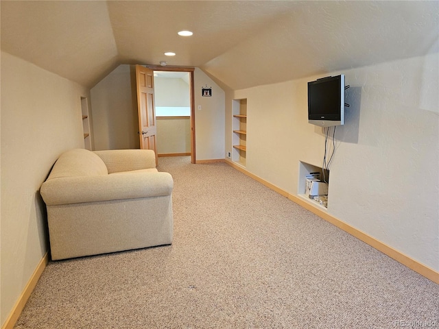 living area featuring light carpet, built in shelves, lofted ceiling, and baseboards