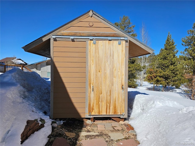 snow covered structure featuring an outbuilding