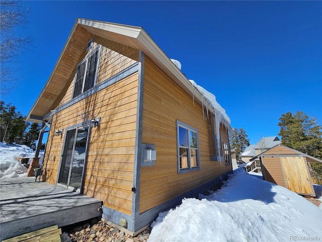 view of snow covered exterior featuring an outbuilding and a storage shed