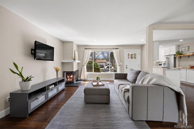 living room with recessed lighting, baseboards, a large fireplace, and dark wood finished floors
