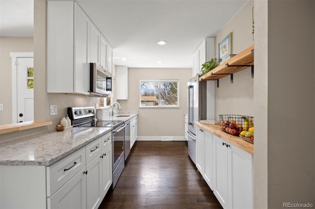 kitchen featuring dark wood-type flooring, open shelves, stainless steel appliances, white cabinets, and baseboards