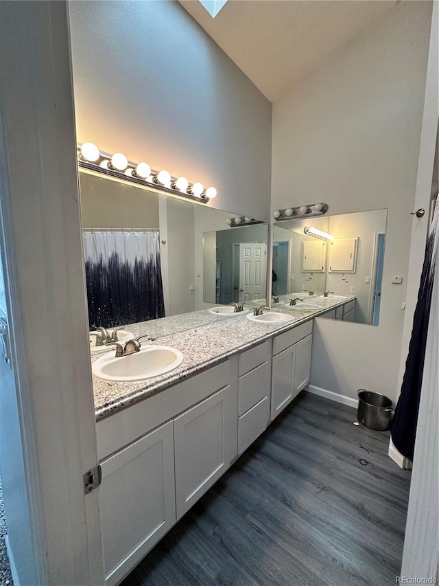 full bath with high vaulted ceiling, double vanity, a sink, and wood finished floors