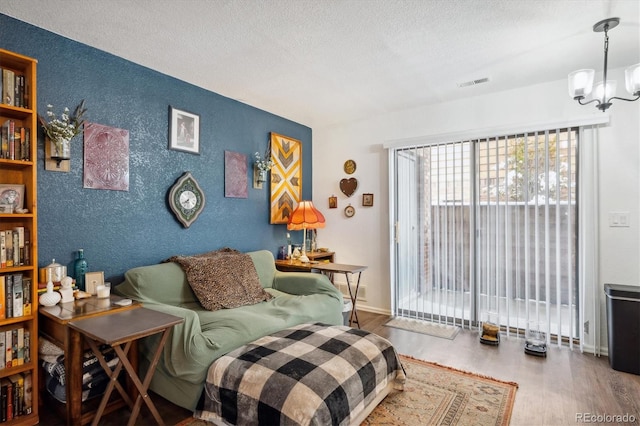 sitting room with a textured ceiling, hardwood / wood-style flooring, and a notable chandelier