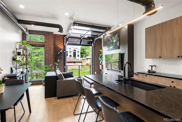 1242 Yates St Unit U2, Denver, CO 80204 - kitchen with light wood finished floors, dark stone counters, brick wall, modern cabinets, and a kitchen bar