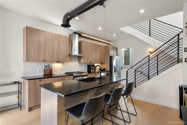 1242 Yates St Unit U2, Denver, CO 80204 - kitchen featuring wall chimney range hood, stainless steel appliances, dark countertops, a breakfast bar, and recessed lighting
