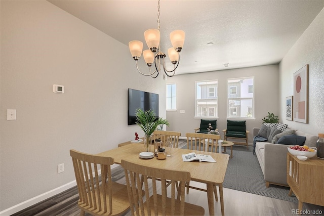 dining room featuring a textured ceiling, dark wood-type flooring, and a chandelier