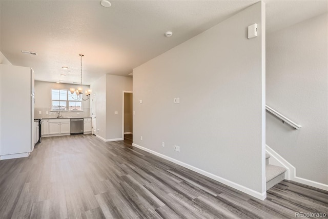 unfurnished living room featuring a chandelier, hardwood / wood-style floors, and sink