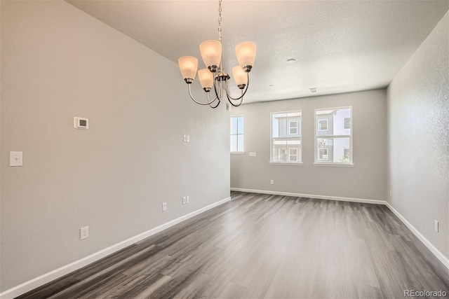 empty room with dark hardwood / wood-style flooring and a notable chandelier