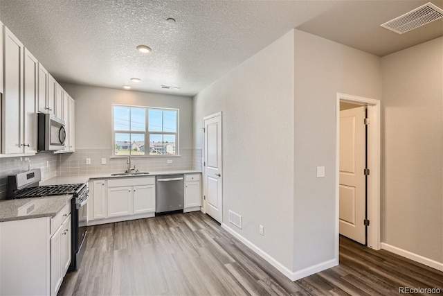 kitchen with hardwood / wood-style floors, stainless steel appliances, white cabinetry, and sink