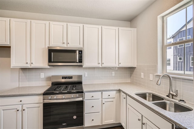 kitchen featuring white cabinetry, sink, appliances with stainless steel finishes, and tasteful backsplash