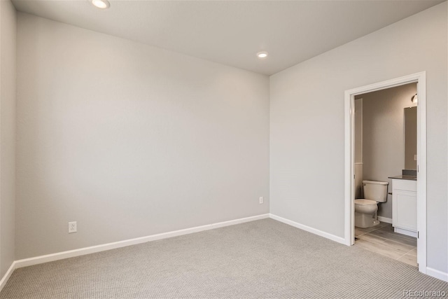 unfurnished bedroom featuring light carpet and ensuite bath