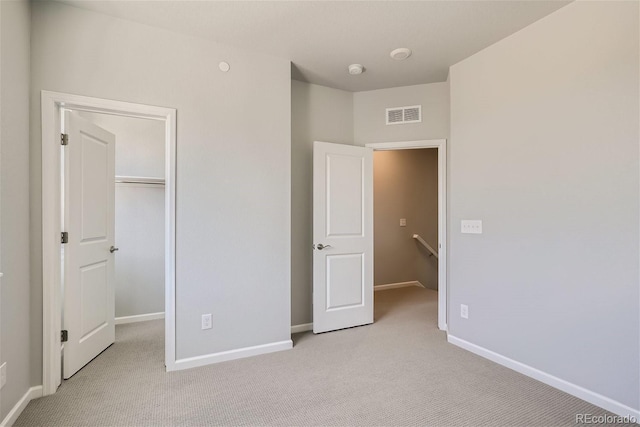 unfurnished bedroom featuring light carpet and a closet