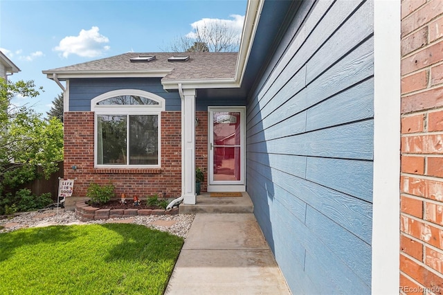 property entrance with fence, brick siding, and a shingled roof