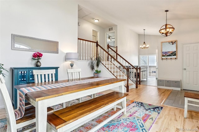 dining space featuring a chandelier, stairway, wood finished floors, a ceiling fan, and baseboards