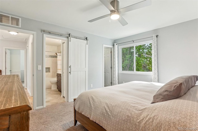 bedroom featuring light carpet, ensuite bath, a barn door, and a ceiling fan