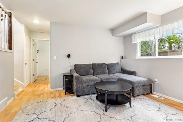 living area featuring wood finished floors, baseboards, and stairs