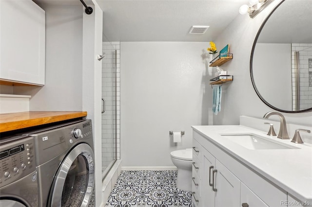 full bath with washing machine and clothes dryer, a shower stall, toilet, and tile patterned floors