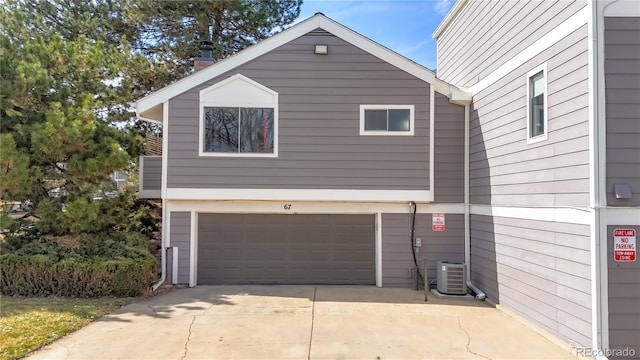 view of side of home featuring central AC unit, driveway, and a garage