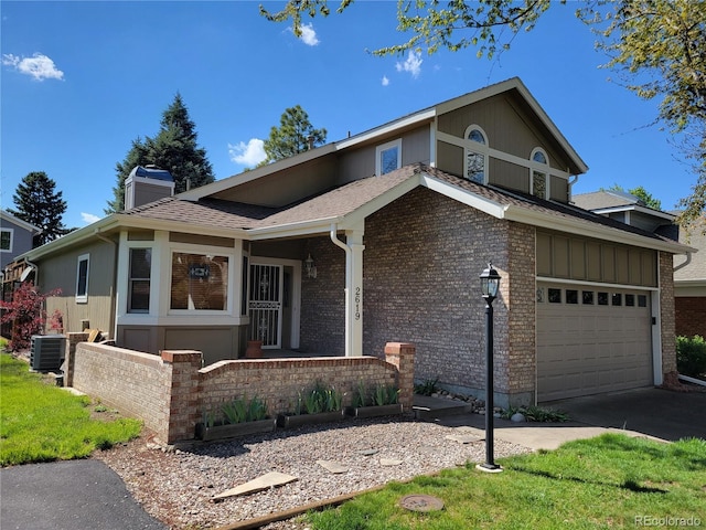 2619 S Iris Ct, Lakewood, CO 80227 - view of front of house with central AC unit, brick siding, a chimney, and asphalt driveway
