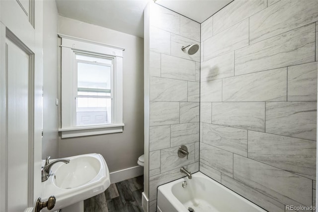 full bathroom with wood-type flooring, tiled shower / bath combo, toilet, and sink