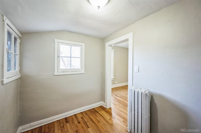 hall with radiator, hardwood / wood-style floors, and vaulted ceiling