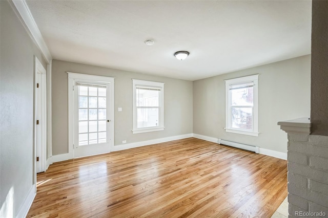 unfurnished living room with light hardwood / wood-style flooring, a wealth of natural light, and a baseboard heating unit