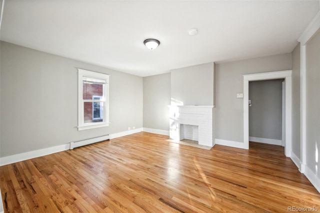 unfurnished living room featuring baseboard heating, a fireplace, and hardwood / wood-style floors