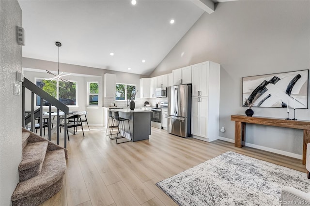 kitchen with light wood finished floors, a kitchen bar, white cabinets, appliances with stainless steel finishes, and a kitchen island