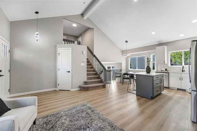 kitchen featuring light countertops, light wood-type flooring, open floor plan, and high vaulted ceiling