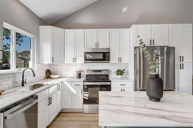 kitchen with a sink, stainless steel appliances, and light stone countertops