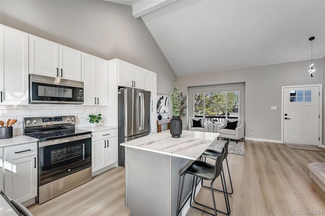 kitchen featuring a center island, high vaulted ceiling, stainless steel appliances, light wood-style floors, and decorative backsplash